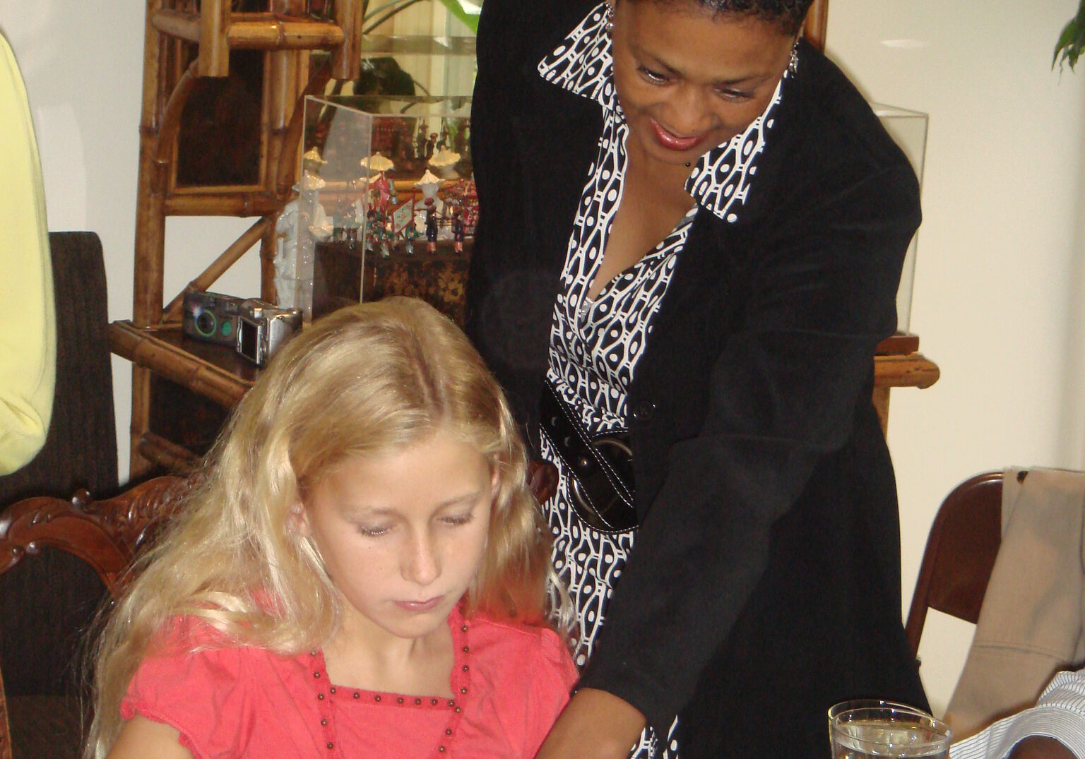 A woman and a girl practicing proper etiquette at a table.